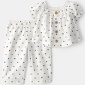 White blouse with blue polka dots and matching pants on a light gray background