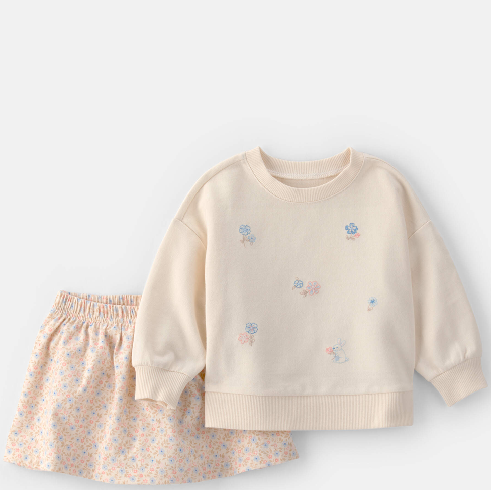 Children's outfit with beige sweatshirt and floral skirt on a light gray background