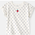White t-shirt with blue polka dots and a red strawberry graphic on a white background