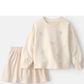 Children's outfit with cream sweatshirt and floral skirt on a white background