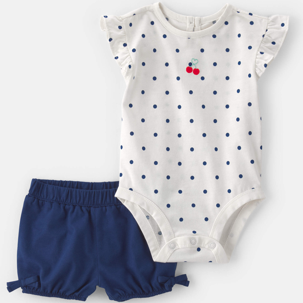 Baby outfit with polka dot romper and navy shorts on a white background