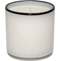 White candle in a glass container with a black rim on a white background