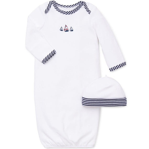 Baby outfit with white long-sleeve shirt and pants, and matching hat, featuring navy stripes and sailboat designs on a white background.