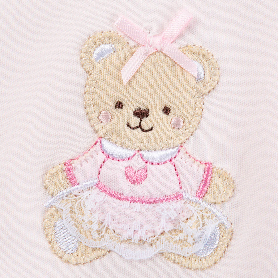 Embroidered teddy bear with a pink dress and bow on a light pink background