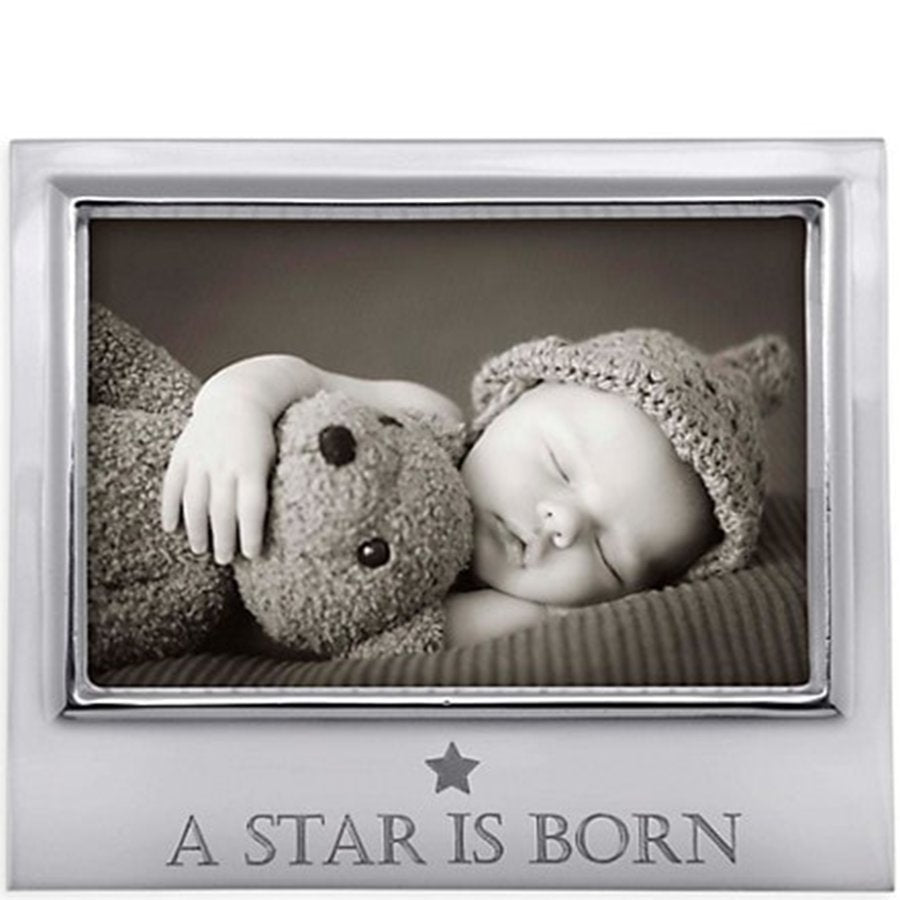 Silver photo frame with a black and white photo of a baby holding a teddy bear, and 'A Star is Born' engraving.