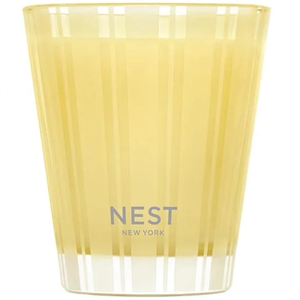 Yellow candle in a glass container with 'NEST New York' branding on a white background