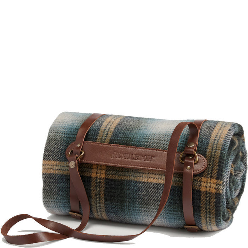 Roll-up plaid blanket with brown leather straps on a white background
