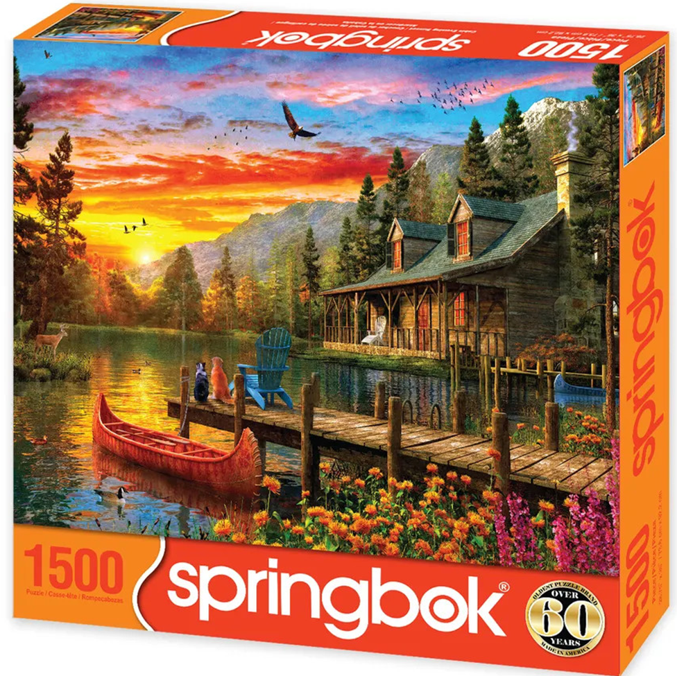 Springbok 1500 pc puzzle Scenic lakeside cabin with dock, red canoe, and colorful sunset.