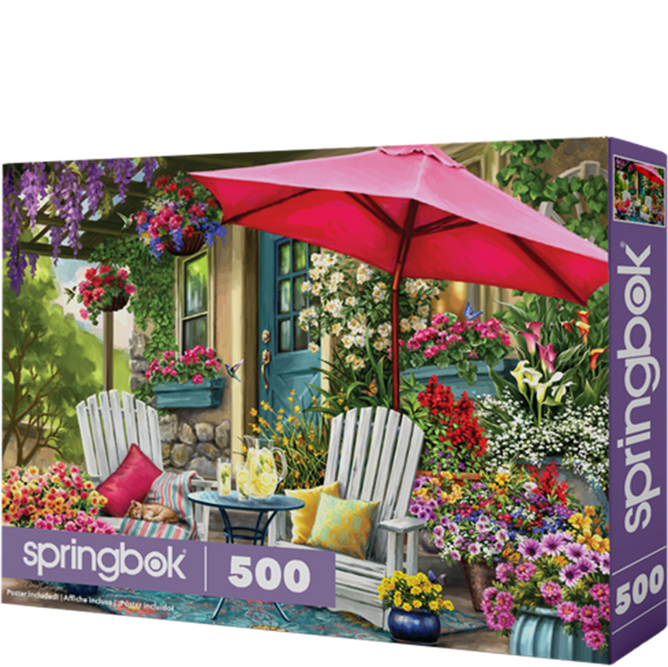 Springbok 500 piece puzzle box with a garden scene featuring a pink umbrella, chairs, and flowers.