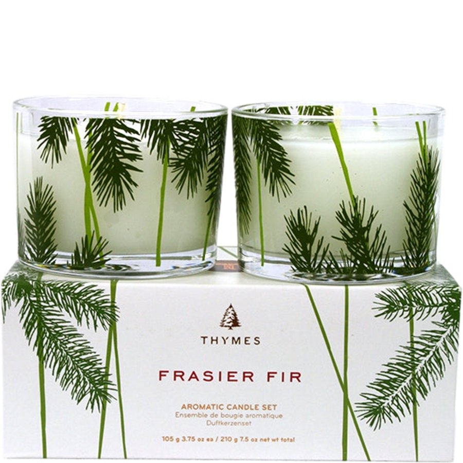 Two candles in clear glass containers with green foliage design on a white box labeled 'Thymes Frasier Fir'.