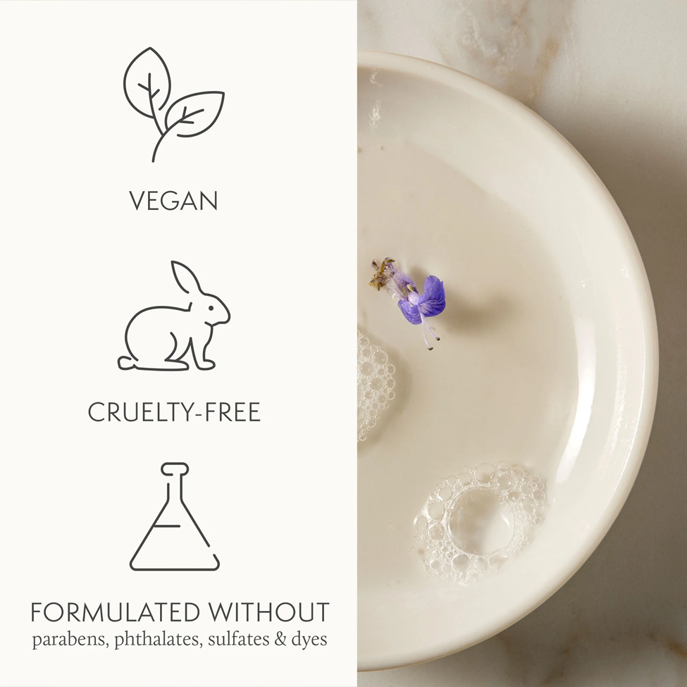 Product with vegan, cruelty-free, and sulfate-free labels next to a bowl of water with a flower.