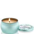 Lighted teal candle in a tin with a matching lid on a white background
