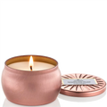 Copper candle with a lit wick and matching lid on a white background