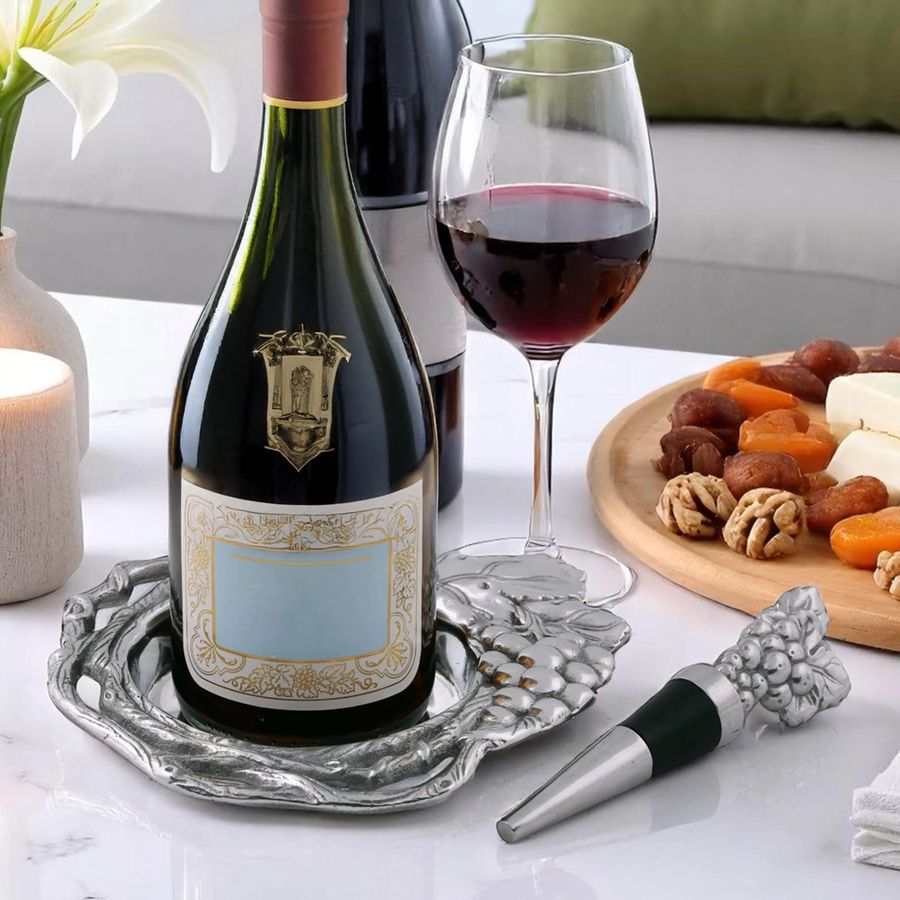 Wine bottle on Arthur Court Grape wine coaster next to wine stopper.