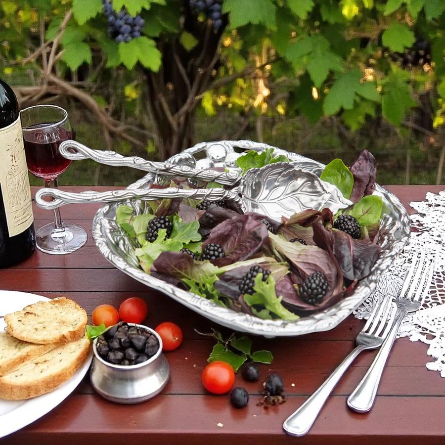 Salad with blackberries, tomatoes, and bread on a wooden table with a bottle of wine and glass.
