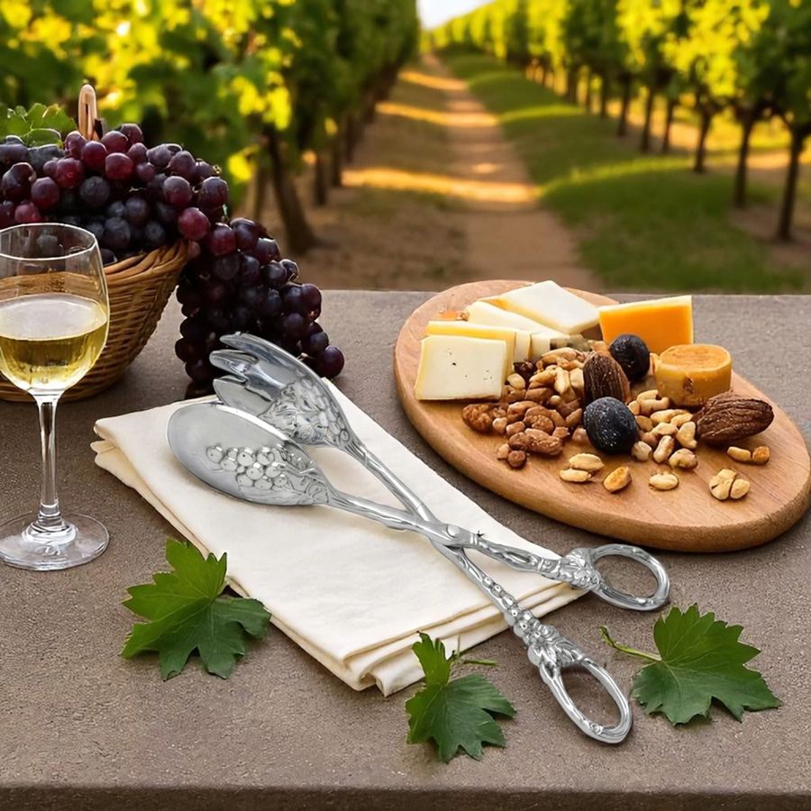 Wine glass with white wine, cheeseboard with snacks, and silver cutlery on a table with vineyard background.
