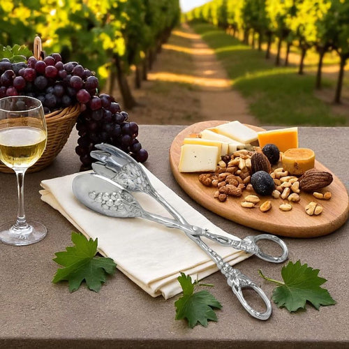 Wine glass with white wine, cheeseboard with snacks, and silver cutlery on a table with vineyard background.