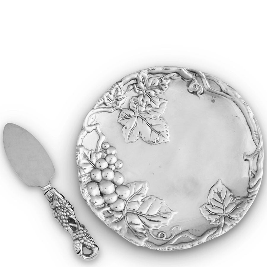 Silver cheese board with grapevine design and matching knife on a white background