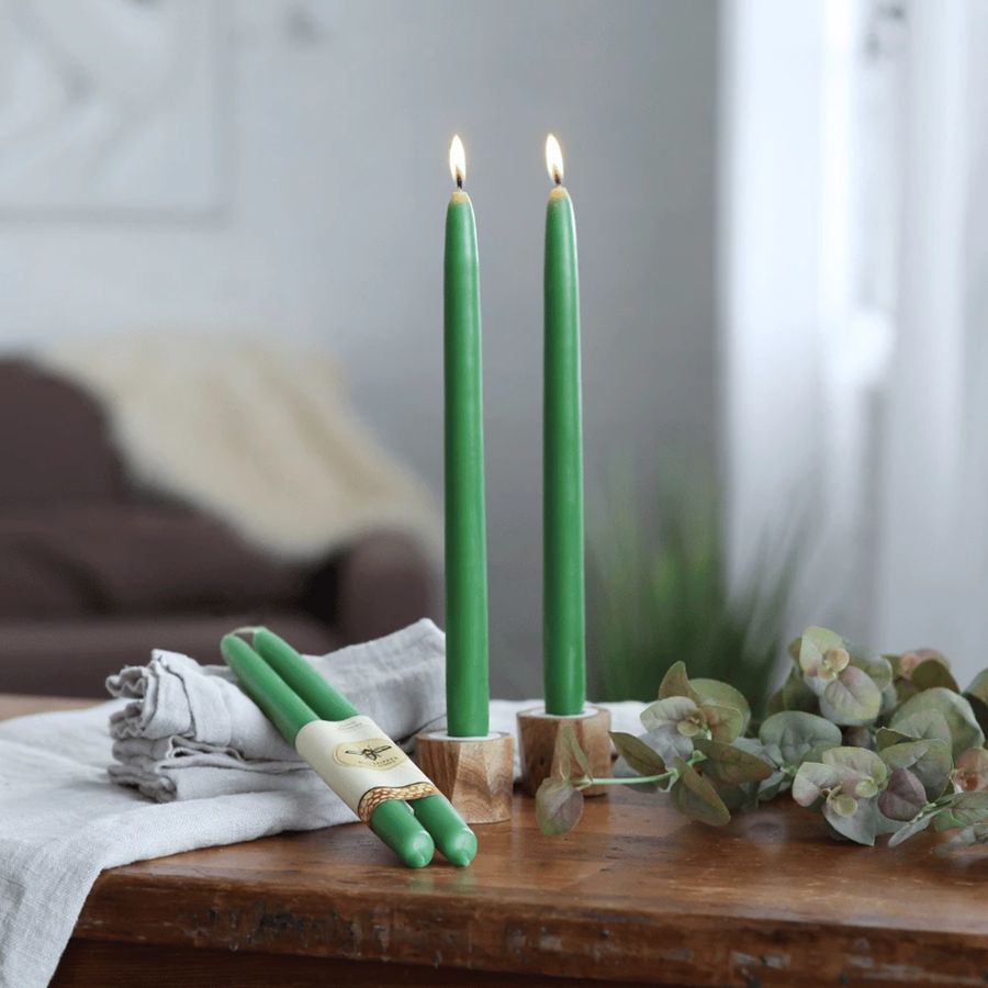 Three green candles on a wooden surface with a blurred background
