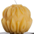 Beeswax candle with intricate braided design on a white background