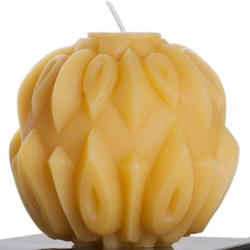 Beeswax candle with intricate braided design on a white background