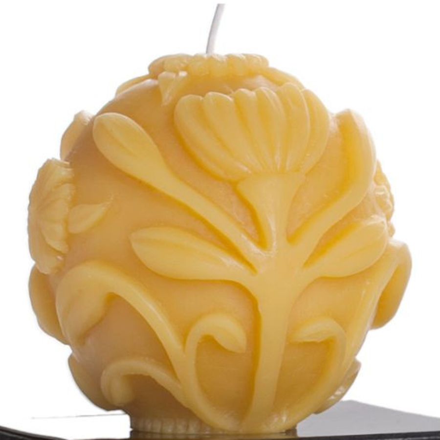 Decorative yellow candle with leaf patterns on a white background