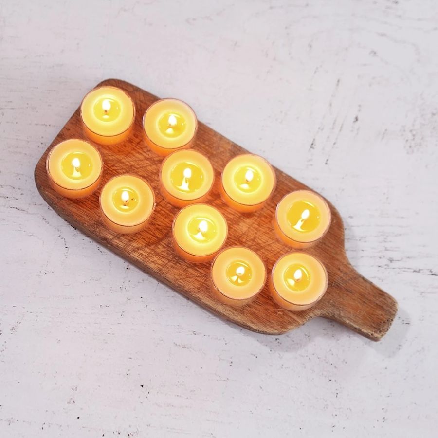 Wooden board with lit candles on a light gray surface