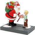 Figurine of Santa Claus handing a candy cane to a child on a white background