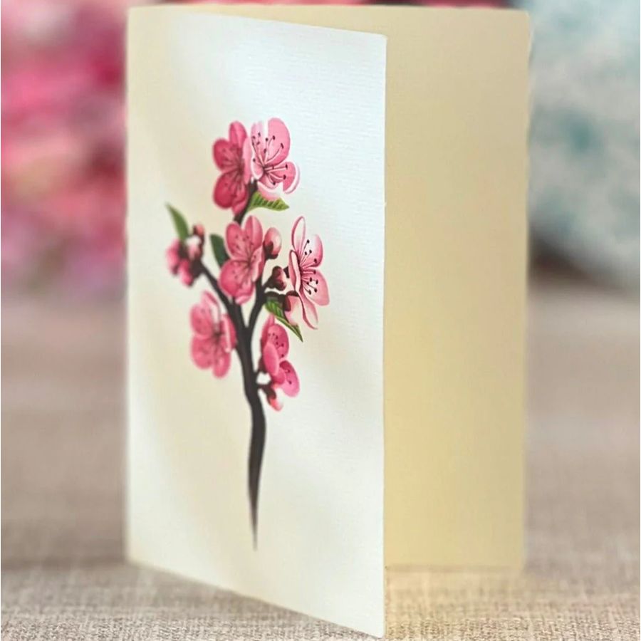 Candle with a pink floral design on a white label against a blurred background