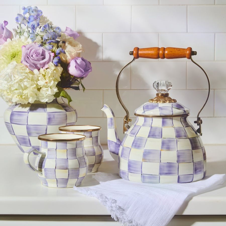 Checkered teapot and cups with a vase of flowers on a tiled wall background