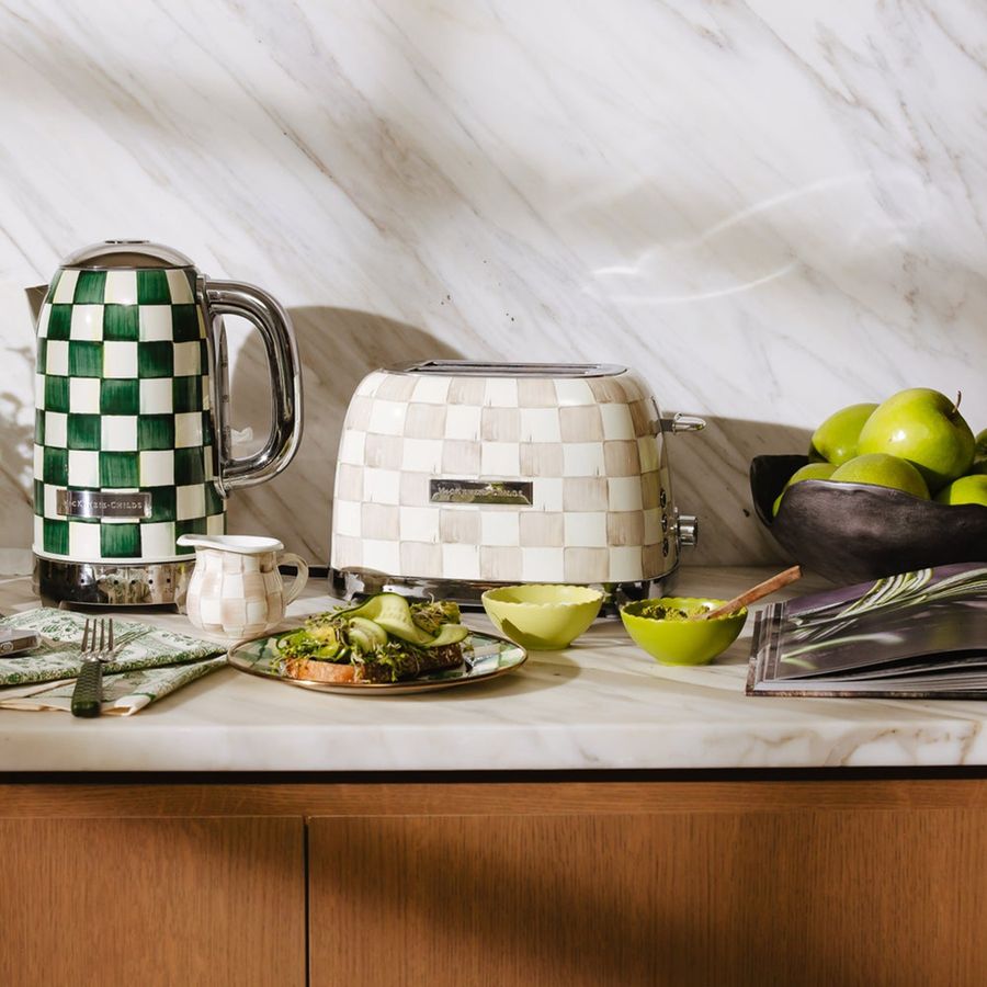Kitchen counter with a toaster, kettle, and food items on a marble countertop.