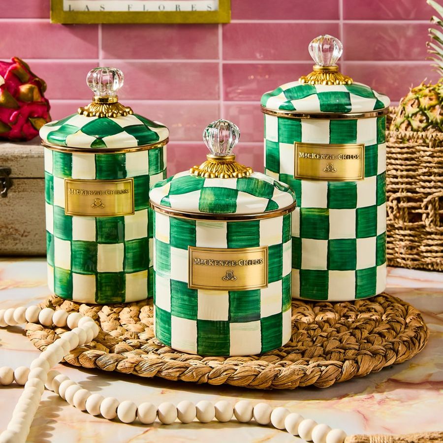 Set of three decorative jars with green and white checkered pattern on a table.