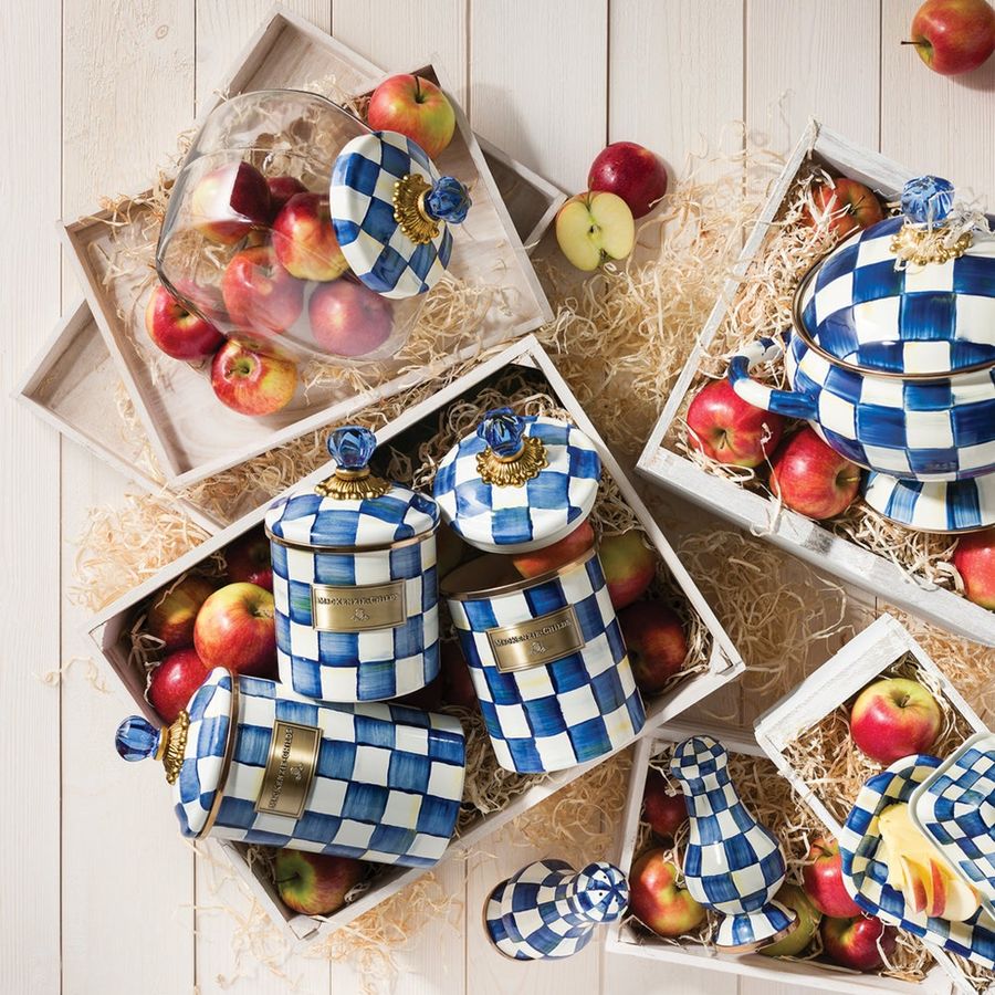 Decorative kitchen canisters with blue and white checkered pattern on a wooden surface with apples.