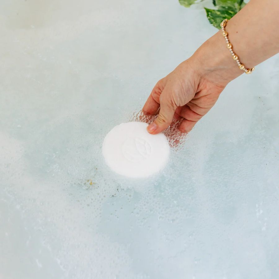 Hand holding a white bath bomb with a blurred background