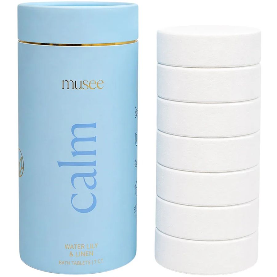Blue cylindrical container labeled 'musee' with 'calm' text, next to a stack of white bath tablets.