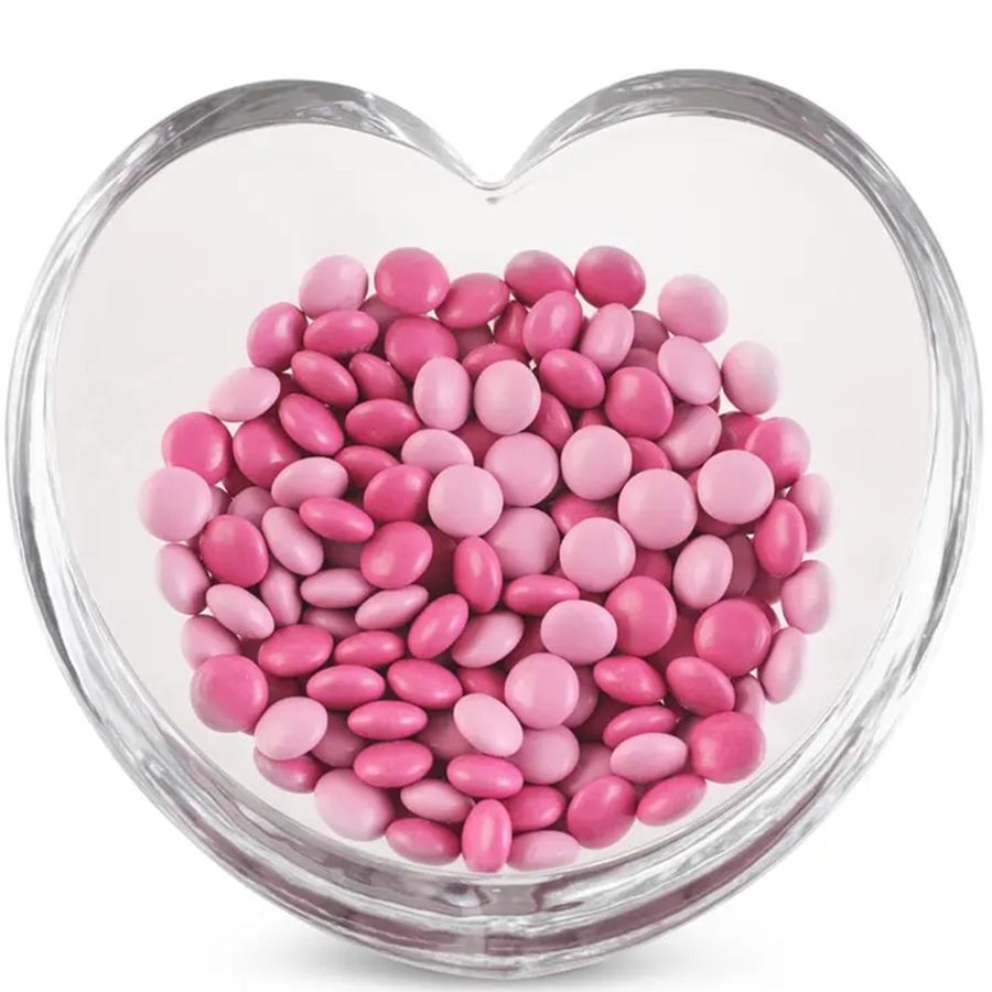 Heart-shaped bowl filled with pink and white candies on a white background