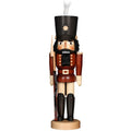 Wooden nutcracker figure with a black hat and a rifle on a white background