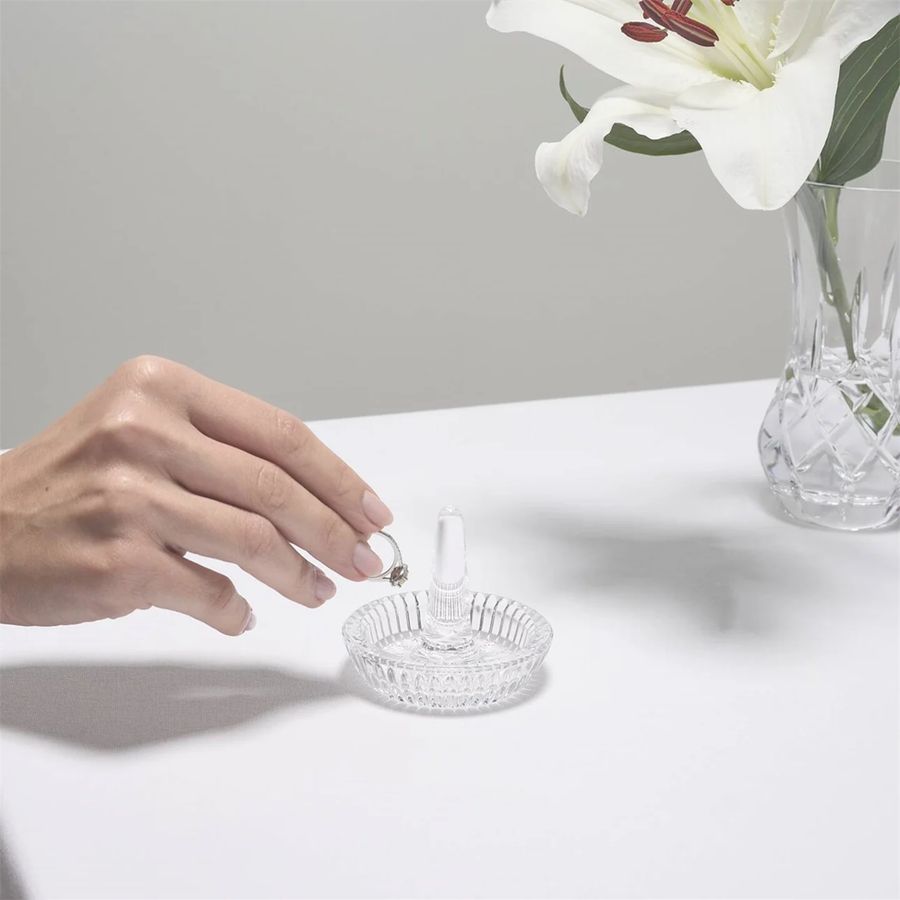A hand placing a ring in a Waterford Round Ring Holder.