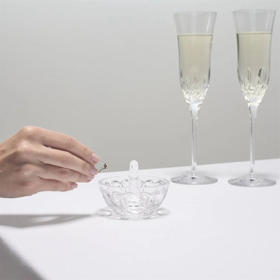 A hand placing a ring in a Waterford Round Ring Holder.