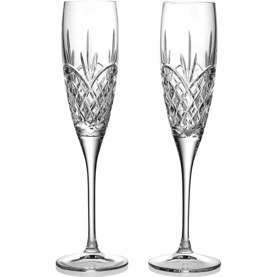 Two crystal champagne flutes with intricate designs on a white background